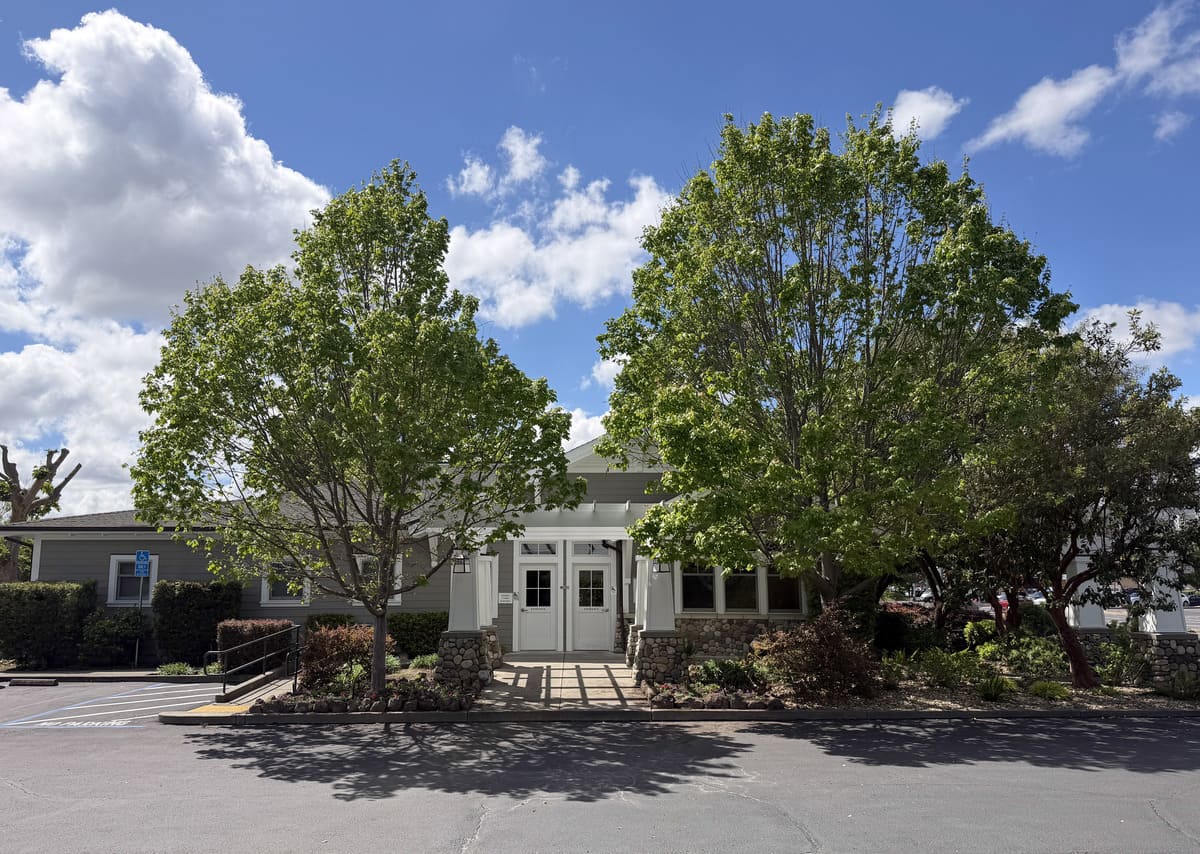 outside of a building entrance with flowers and trees