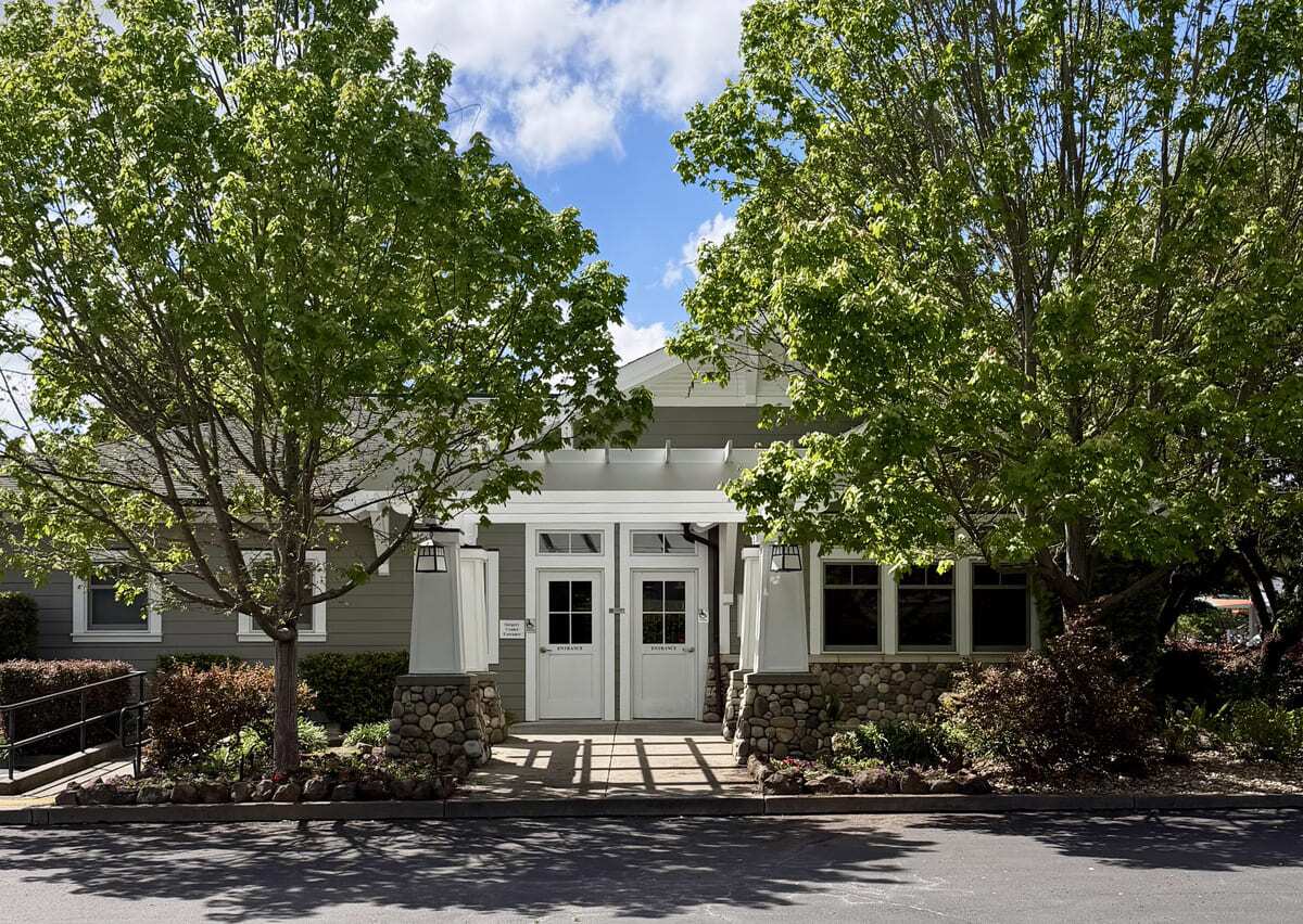 outside of a building entrance with flowers and trees